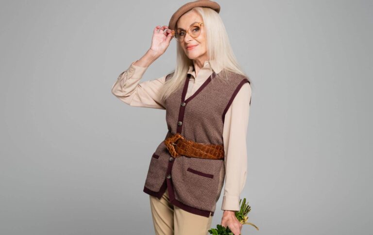 An elegant elderly woman holding flowers and tipping her hat