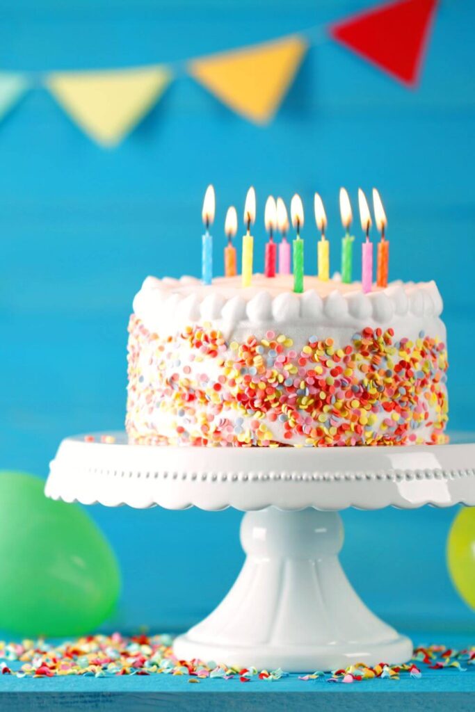 An image of a colourful birthday cake with many candles