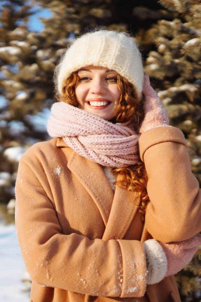 An elegant woman wearing a bulky knit hat and scarf with a a winter coat